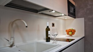 Une cuisine moderne avec un évier blanc, une bouteille de vin et deux verres posés sur le comptoir.