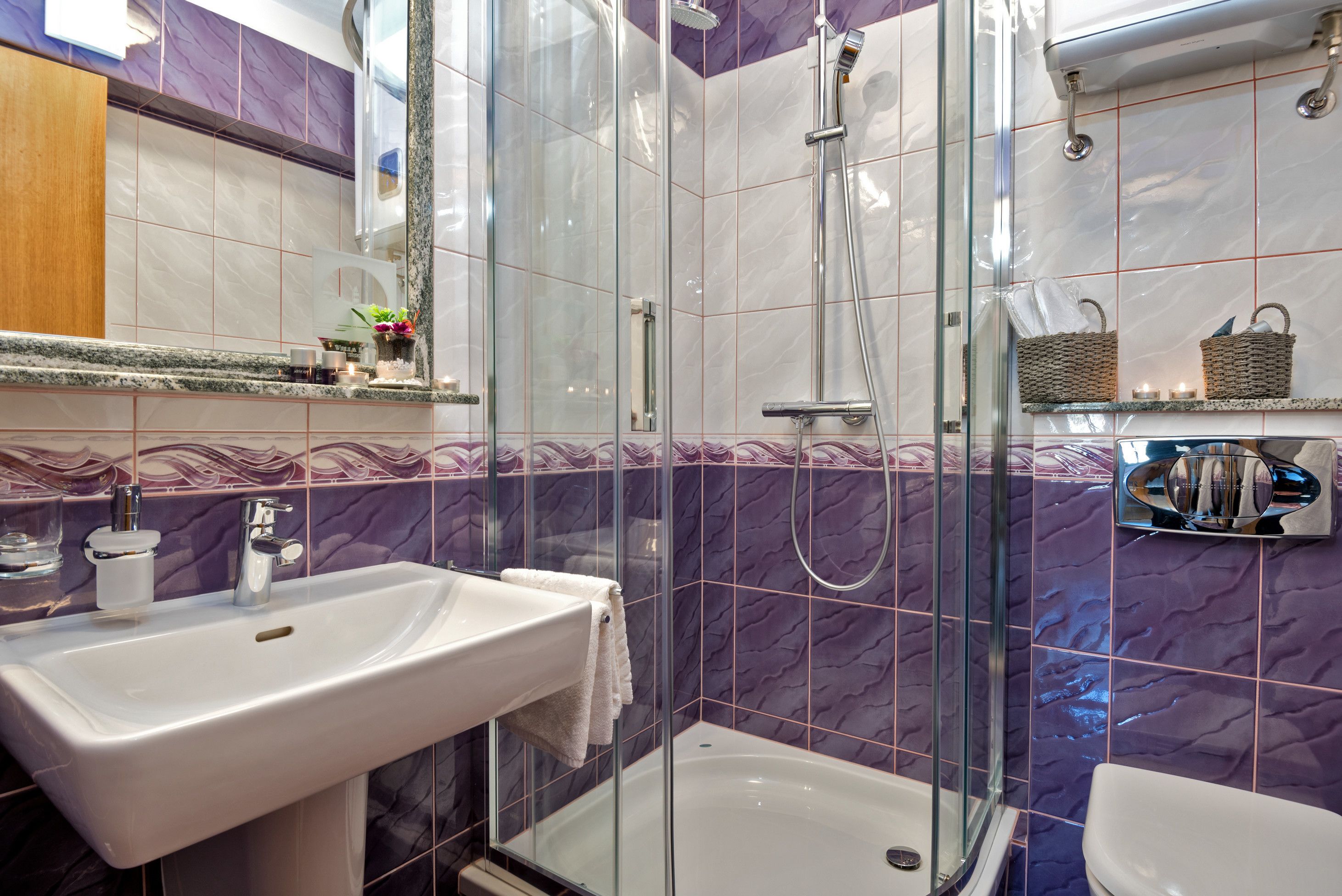A bathroom with a glass-enclosed shower, a sink, and a toilet.