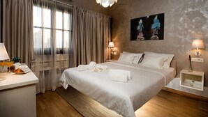 Une chambre d’hôtel avec un grand lit, une table de chevet avec une lampe, une fenêtre avec des rideaux et un tableau au mur.