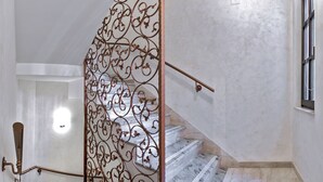 Un escalier orné d’une rampe en métal décoratif et de marches en marbre.