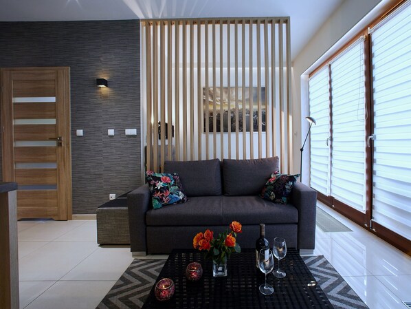 A modern living room with a grey sofa, a black coffee table, and a decorative vase with flowers.