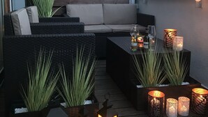 A rooftop patio with outdoor furniture, decorative candles, and string lights. - 4UApart - Apartment studio Platan New York (Swinoujscie)