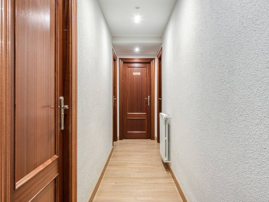 A hallway with wooden doors and a radiator on the wall.