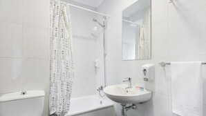 A modern bathroom with a toilet, bathtub, and sink. - Hostal Uria (Salamanca)