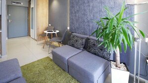 Un salon moderne avec un canapé gris, une petite table ronde et une plante en pot.