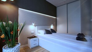 Un dormitorio moderno con cama, mesitas de noche y una planta en maceta.