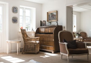 Une pièce avec un buffet en bois, des chaises en osier et une table à manger.