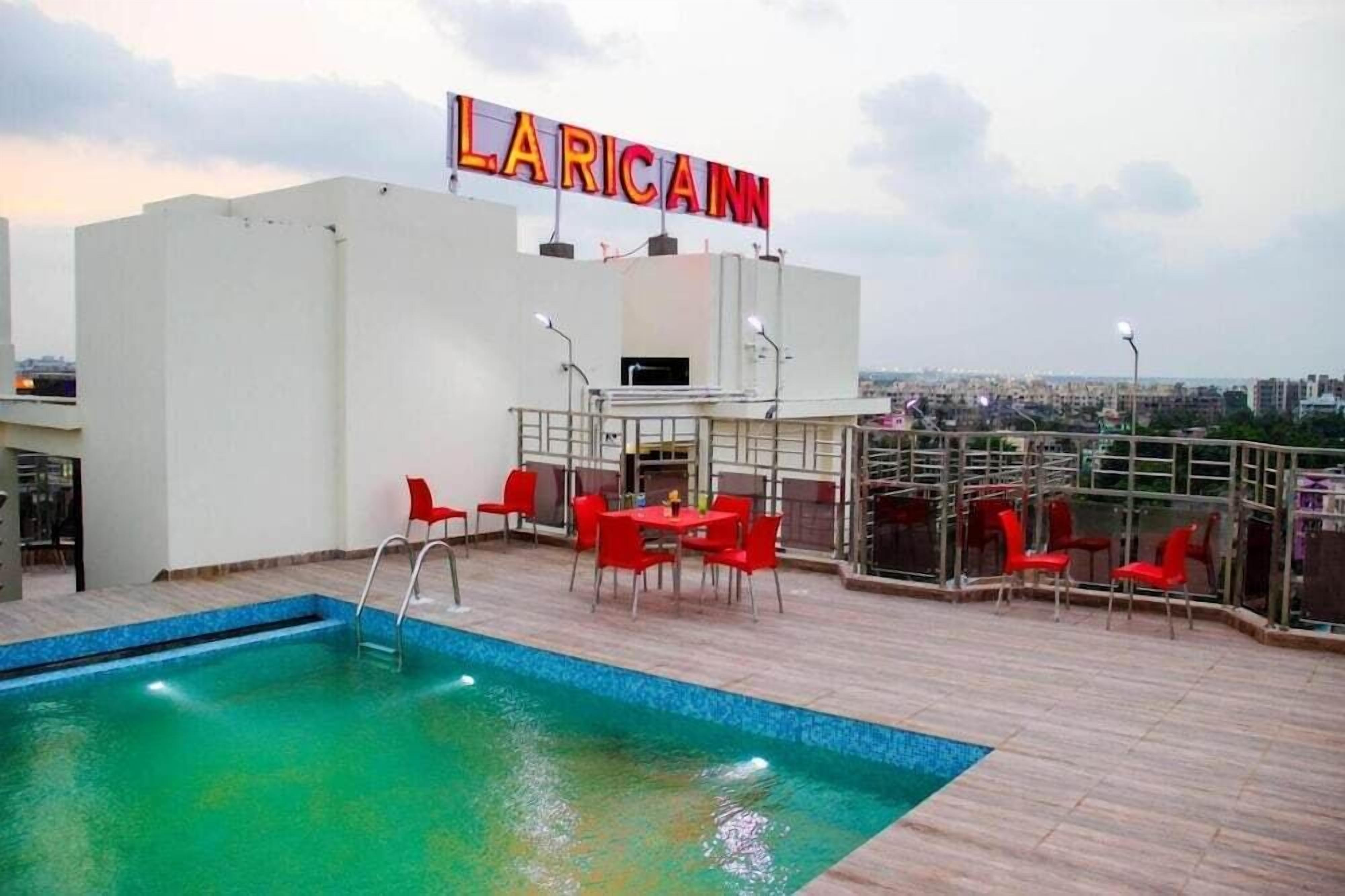 Zona de piscina al terrat amb cadires vermelles i un cartell que diu 'LARICANN'.