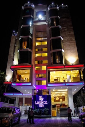 A multi-story hotel with a prominent entrance and a neon sign. - Regenta Inn Larica (Barasat)