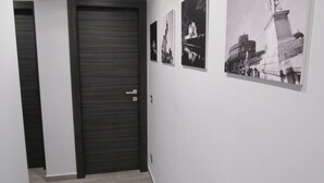 Ein Flur mit einer geschlossenen Tür, einem Lichtschalter und drei schwarz-weißen Fotografien an der Wand.
