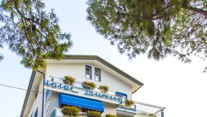 A hotel with multiple balconies, a sign reading "HOTEL TOURING," and outdoor seating. - Hotel Touring (Jesolo)