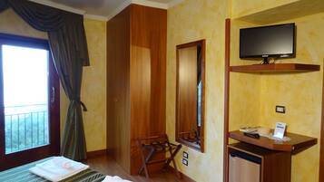 Une chambre d’hôtel avec un lit, un bureau, une télévision et une fenêtre avec des rideaux.