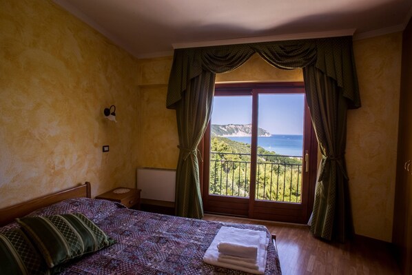 A bedroom with a bed, a nightstand, and a window with curtains.