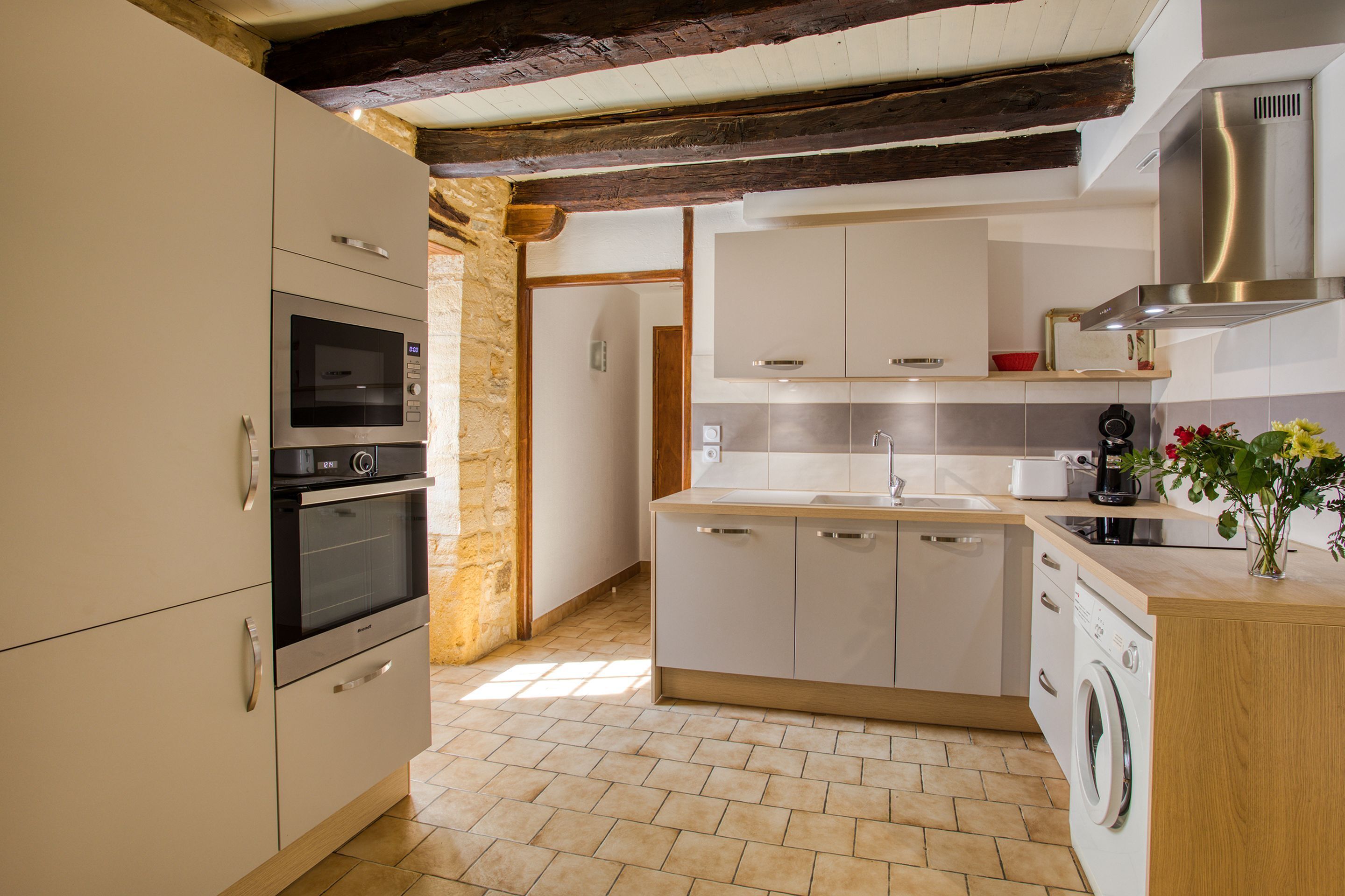 A modern kitchen with built-in appliances, a central island, and a stone wall.