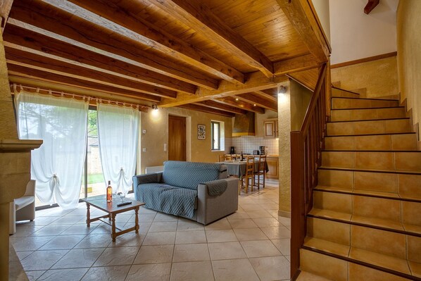 A spacious living area with a wooden ceiling, a sofa, a coffee table, and a staircase. - Combas Village De Gites (Saint-Crepin-et-Carlucet)