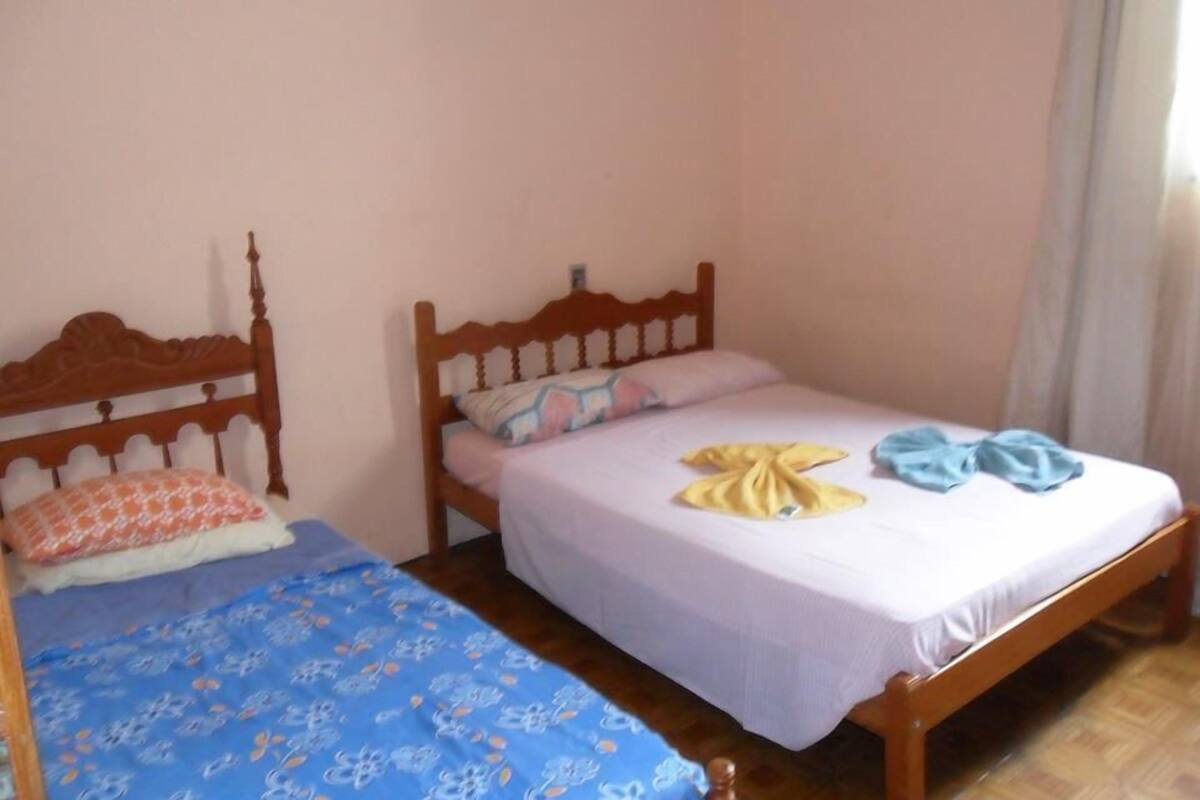 Une chambre à coucher avec deux lits, chacun doté d’une tête de lit en bois, d’un matelas blanc et d’une couvre-lit bleue.