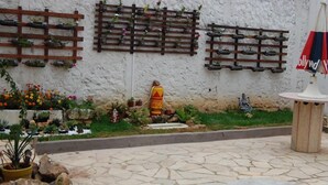Ein Innenhof mit Steinpflaster, Blumentöpfen, einer Zierfontäne und einer Statue.