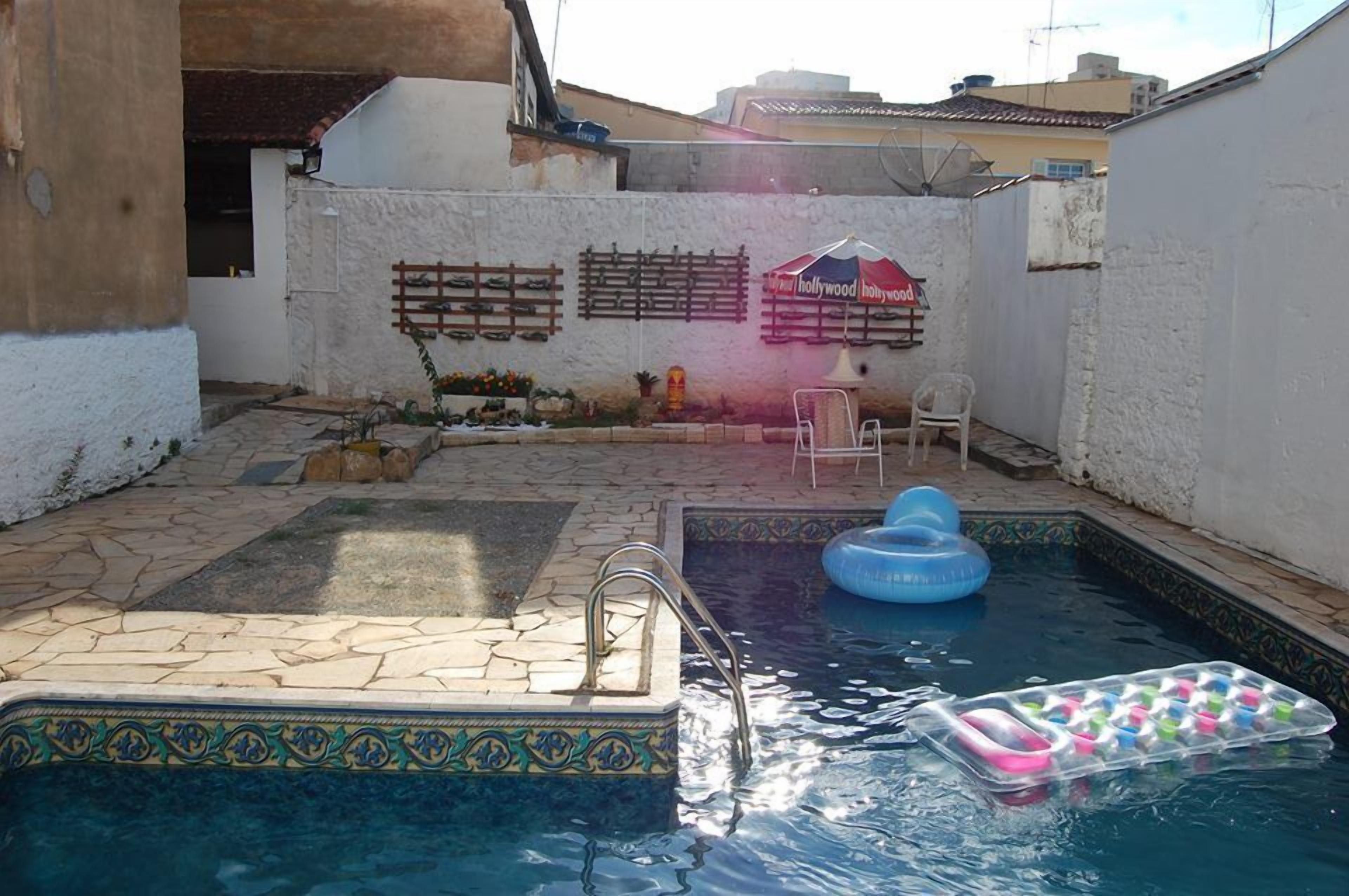 Piscina com deck revestido, um flutuador inflável pequeno e uma cadeira de descanso.