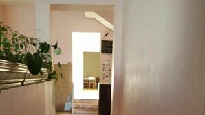 Ein Korridor mit Fliesenboden, der zu einem Zimmer mit Bett und Schreibtisch führt.