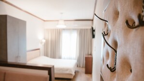 Una habitación de hotel con cama, sofá, televisión y un gancho en la pared.