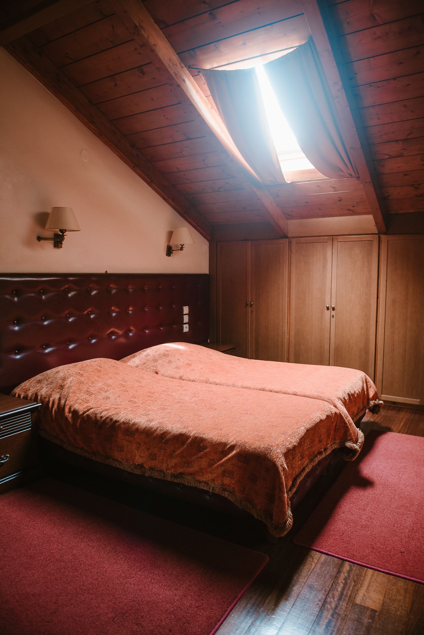 Un dormitorio con una cama grande, vigas de techo de madera y un tragaluz.