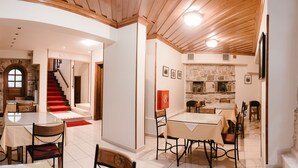 Un comedor amplio con chimenea de piedra, una escalera que sube a un nivel superior y una cocina moderna visible a través de una puerta abierta.