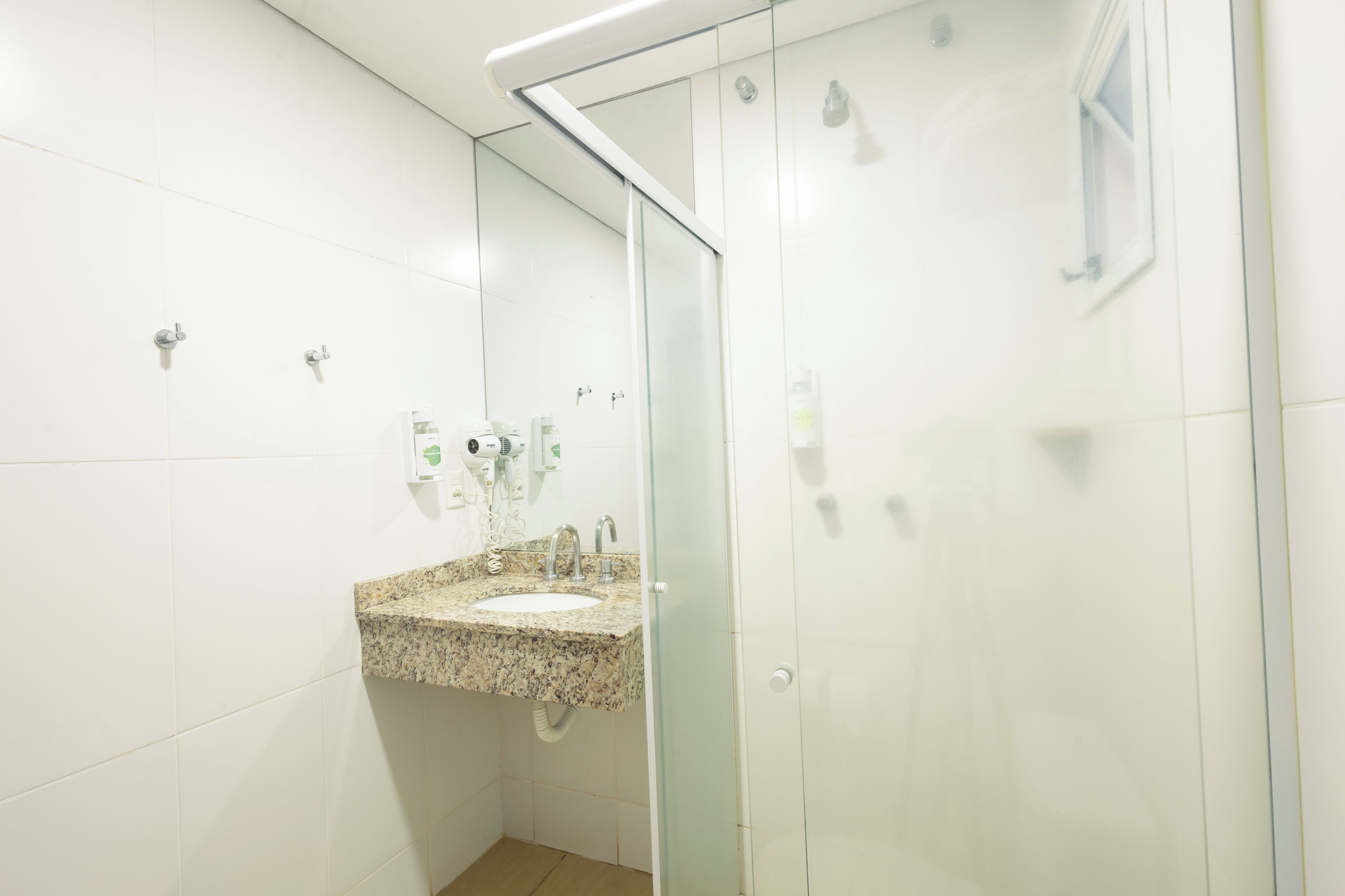 A bathroom with a granite countertop sink, a glass shower enclosure, and a mirror.