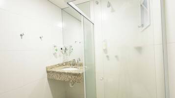 A bathroom with a granite countertop sink, a glass shower enclosure, and a mirror.