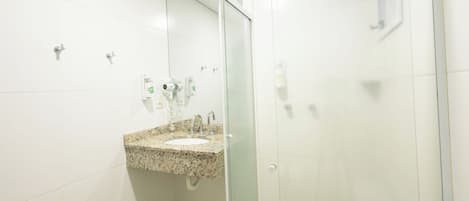 Baño con lavamanos de encimera de granito, cabina de ducha de vidrio y espejo.