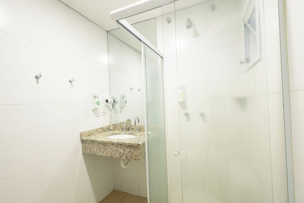 Baño con lavamanos de encimera de granito, cabina de ducha de vidrio y espejo.