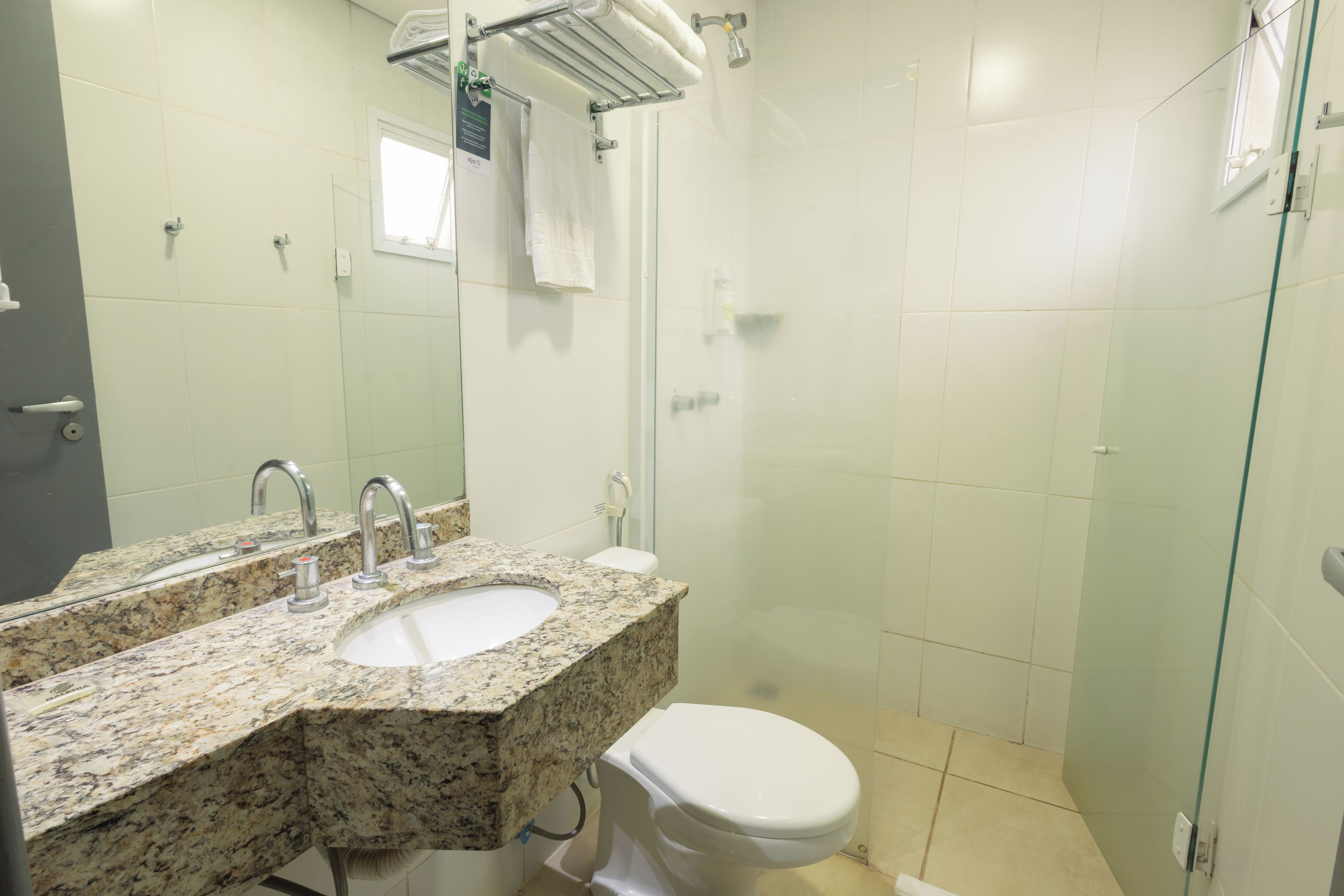 Un baño con lavamanos de encimera de granito, un espejo, inodoro y cabina de ducha de vidrio.