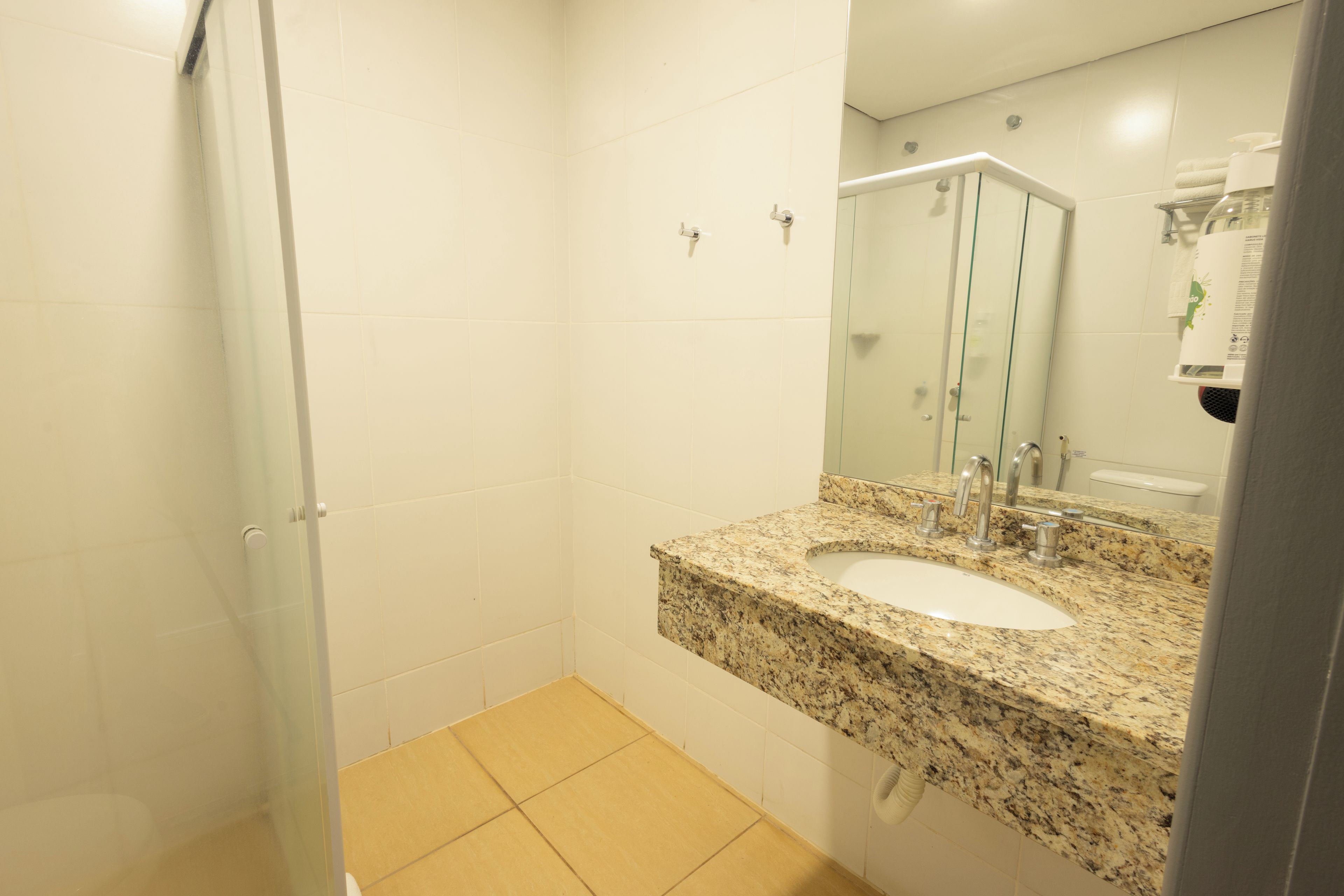 A bathroom with a granite sink, a glass shower enclosure, and a mirror above the sink.