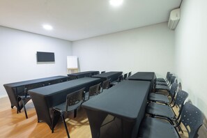 A conference room with multiple tables and chairs, a whiteboard, and an air conditioning unit on the wall. - Transamerica Fit Jaú (Jau)