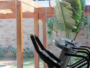 A stationary exercise bike with a wooden structure in the background. - Transamerica Fit Jaú (Jau)