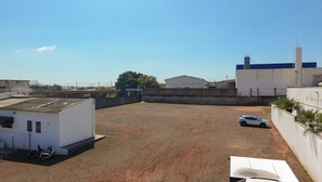 An open parking area with a white building, a white car, and a motorcycle.