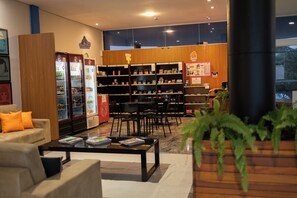 Um interior moderno com área de estar, máquina de vendas e estante de livros.