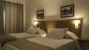 Ein Hotelzimmer mit zwei Betten, einem Kopfteil, Wandleuchten und einem gerahmten Bild an der Wand.
