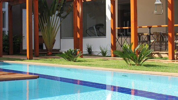 Piscina con una pérgola de madera y un patio amueblado al aire libre.