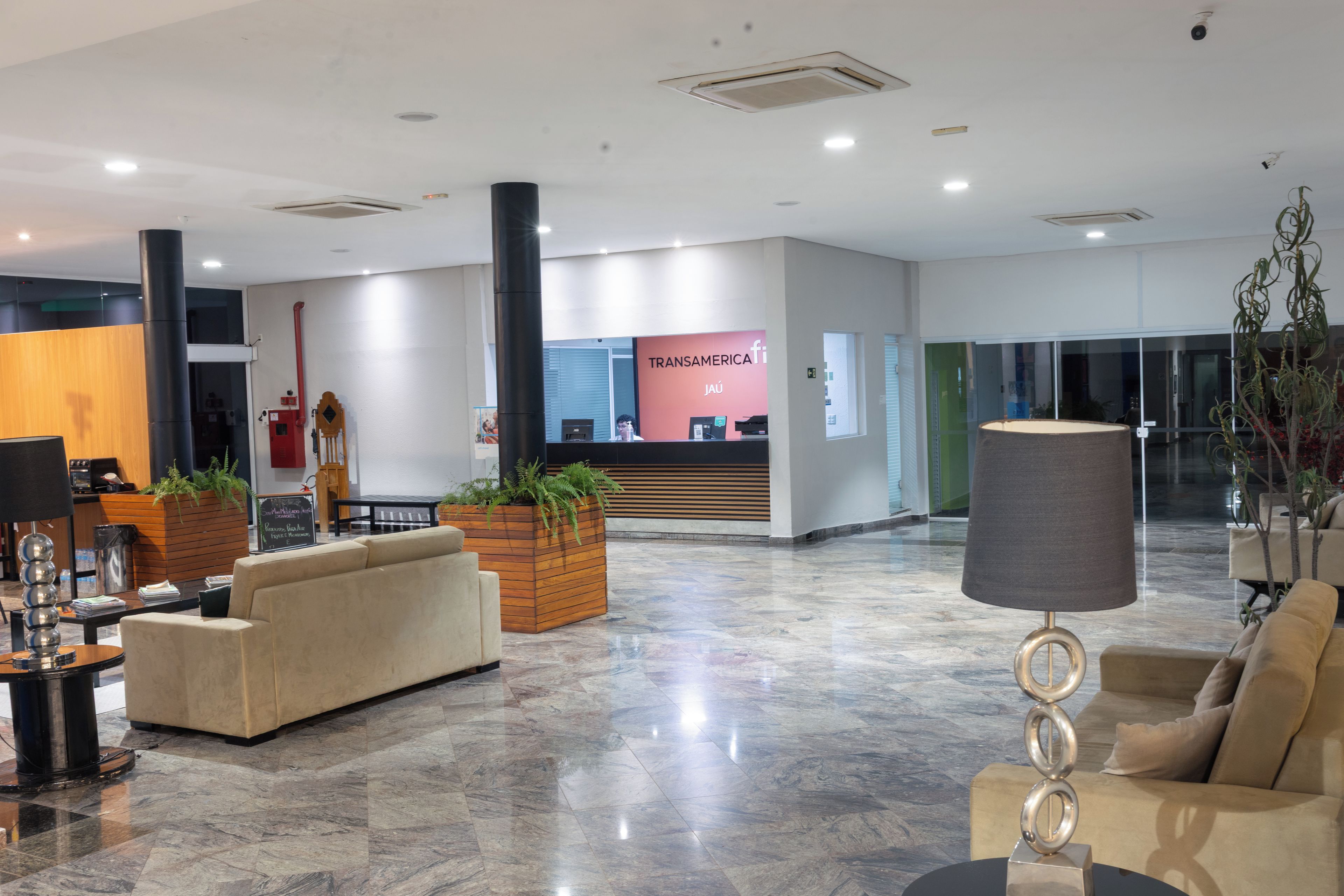 En moderne lobby med reception, siddeområde og en stor plante.