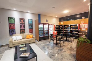 A lobby with a sofa, coffee table, and bookshelves. - Transamerica Fit Jaú (Jau)