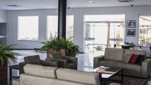A spacious lobby with large windows, a central black column, and a seating area with sofas and a coffee table. - Transamerica Fit Jaú (Jau)
