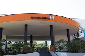 A building with a curved orange facade and the name 'TRANSAMERICAfit' on it. - Transamerica Fit Jaú (Jau)