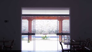 An interior view of a restaurant with a large glass door leading to an outdoor patio area. - Transamerica Fit Jaú (Jau)
