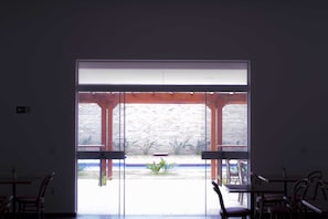 An interior view of a restaurant with a large glass door leading to an outdoor patio area. - Transamerica Fit Jaú (Jau)