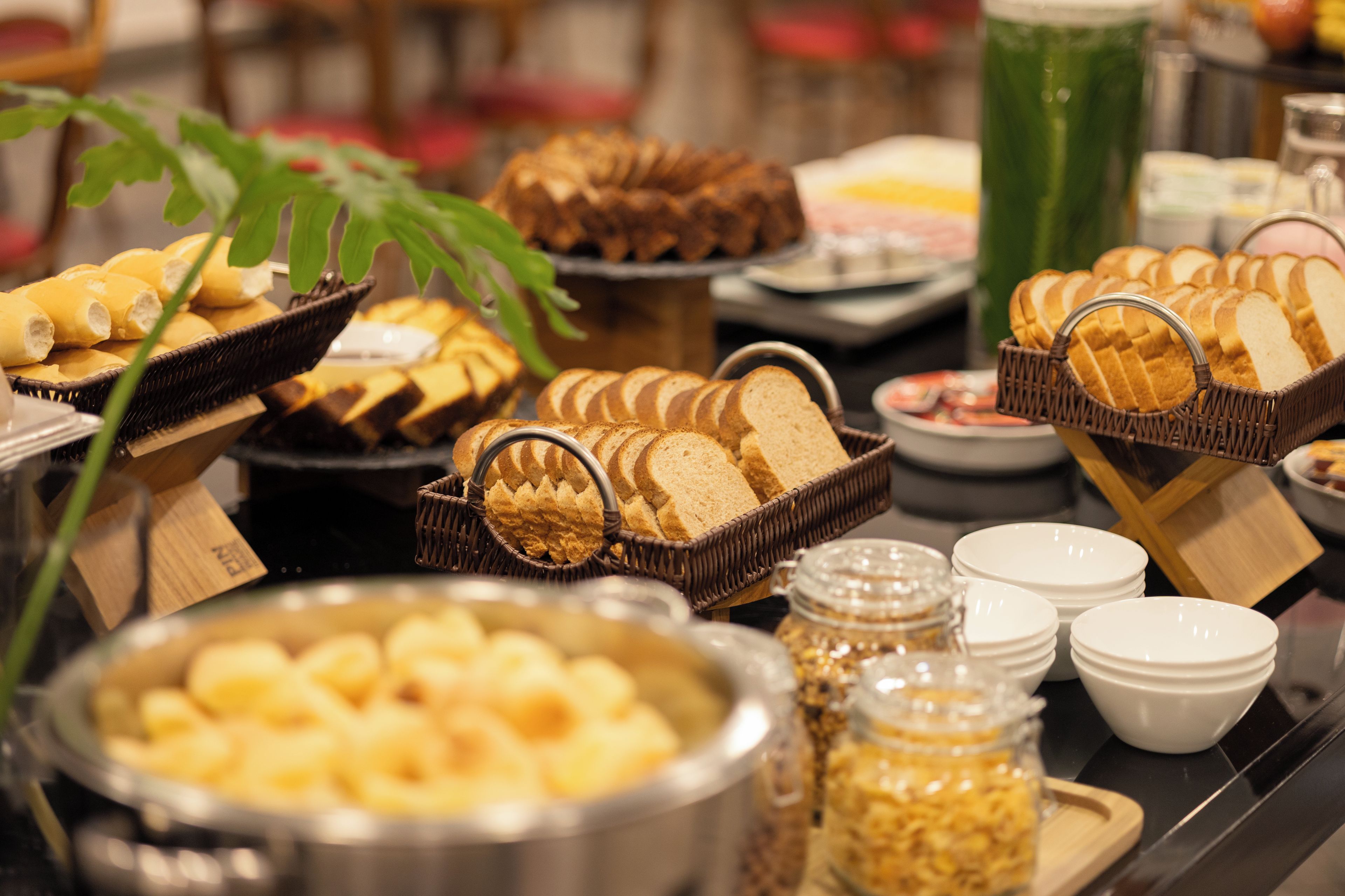 A buffet with various food items including bread, pastries, and a bowl of what appears to be fruit.