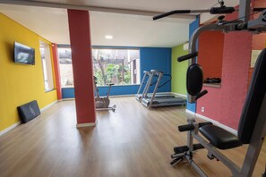 A gym with exercise equipment, a TV, and a window with a view of greenery. - Transamerica Fit Jaú (Jau)