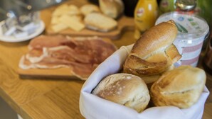 A wooden table with various food items including bread, pastries, and a container of butter. - FeelinRome Bed & Breakfast (Rome)