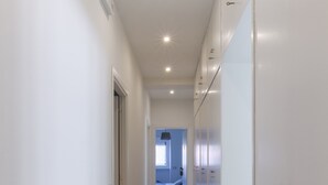 A narrow hallway with white walls and wooden flooring, leading to a bedroom with a bed and a window. - FeelinRome Bed & Breakfast (Rome)