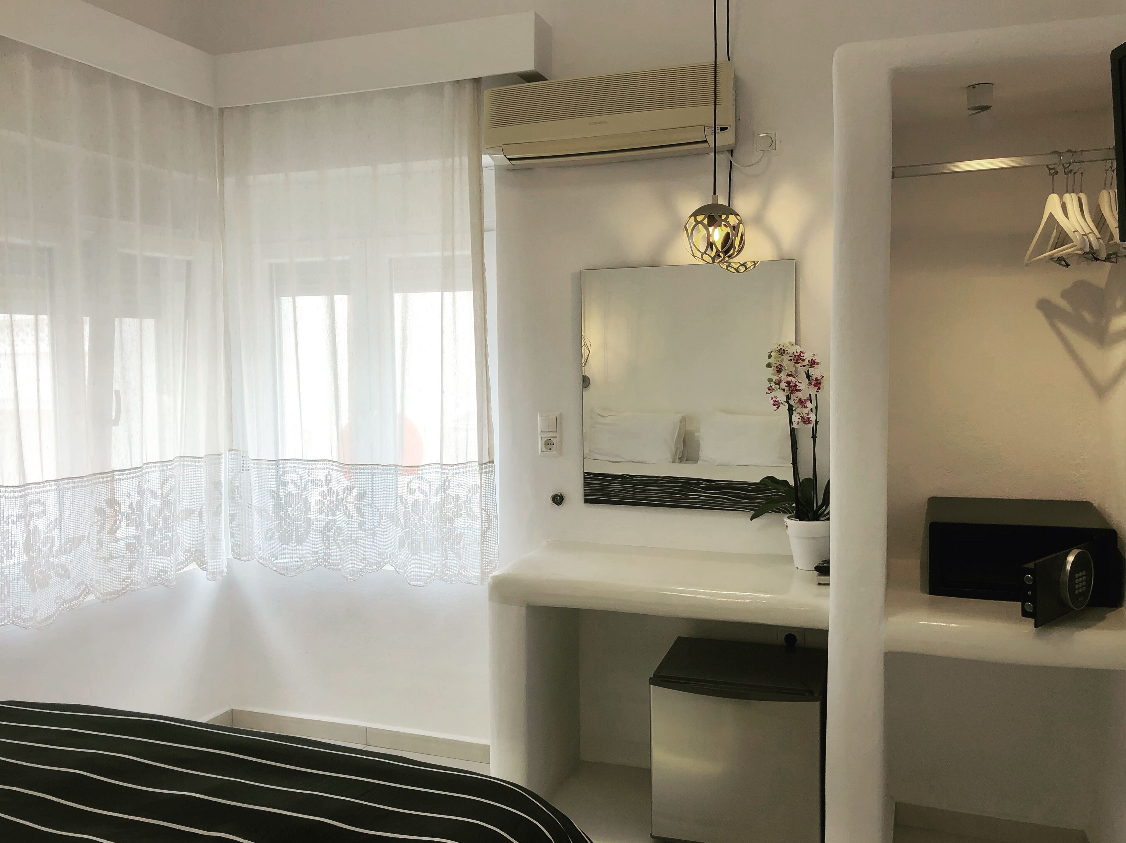 Un baño moderno con lavamanos blanco, espejo y una orquídea en maceta.