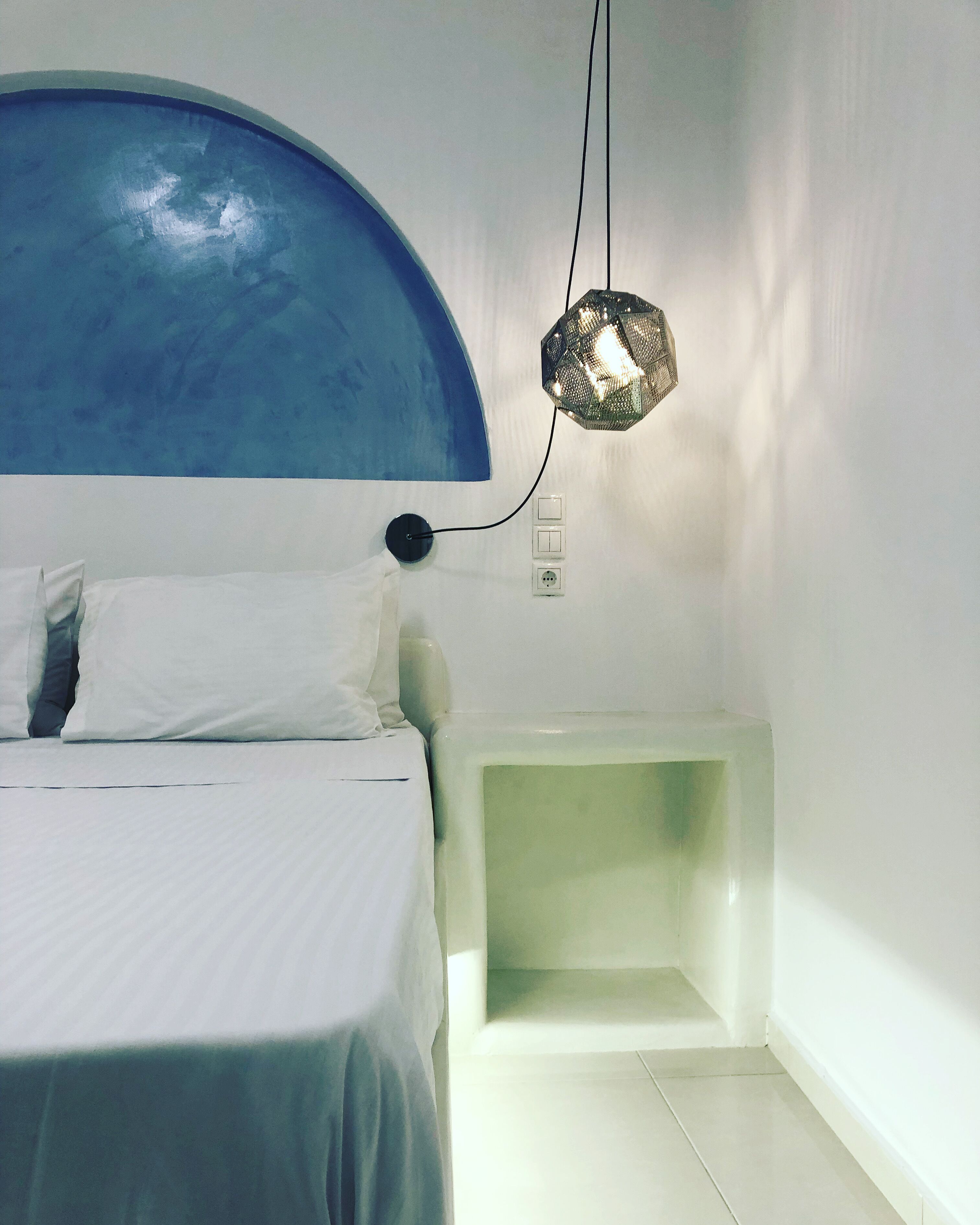 Ein Schlafzimmer mit einem Bett, einem Nachttisch, einer Wandlampe und einer Steckdose.
